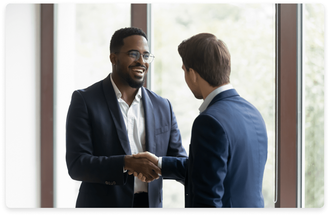 
                  Two professionals in business attire shaking hands in a well-lit office,
                  exemplifying the partnership and trust established through fractional CFO
                  services for marketing companies.
                